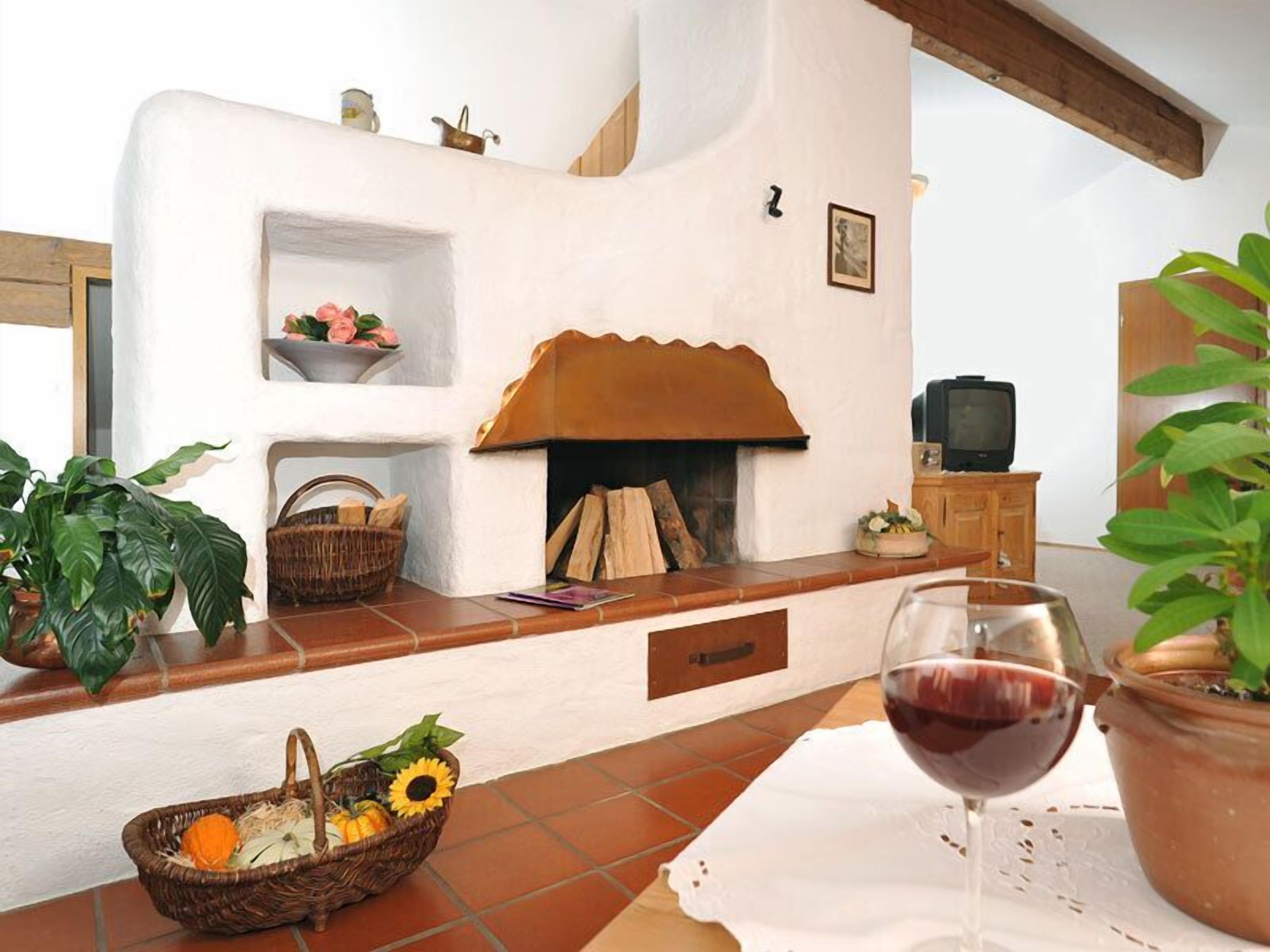 A cozy living room with a fireplace, a television, and a table with a glass of red wine.