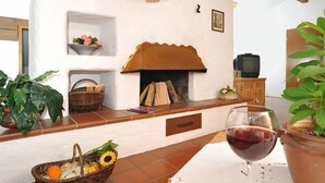 A cozy living room with a fireplace, a television, and a table with a glass of red wine. - "DEPENDANCE BERGSTÜBERL" 102 (Reit im Winkl)