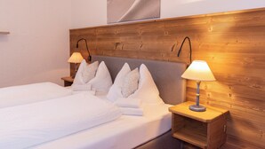 A double bed with white linens and pillows, two bedside tables with lamps, and a wooden headboard. - "DEPENDANCE BERGSTÜBERL" 102 (Reit im Winkl)