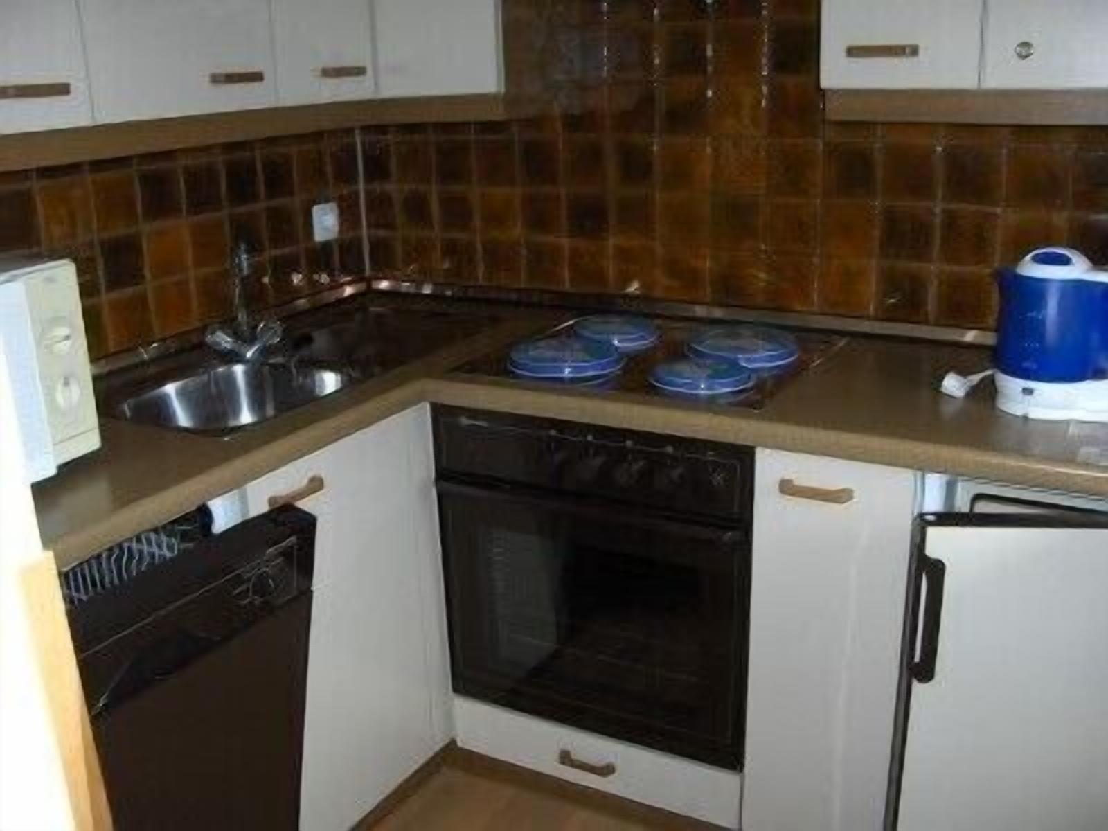 Een kleine keuken met een fornuis, spoelbak en een afdruiprek.