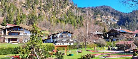 A mountain resort with chalet-style buildings, a well-maintained garden, and a view of the surrounding forest.