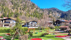 A mountain resort with chalet-style buildings, a well-maintained garden, and a view of the surrounding forest.