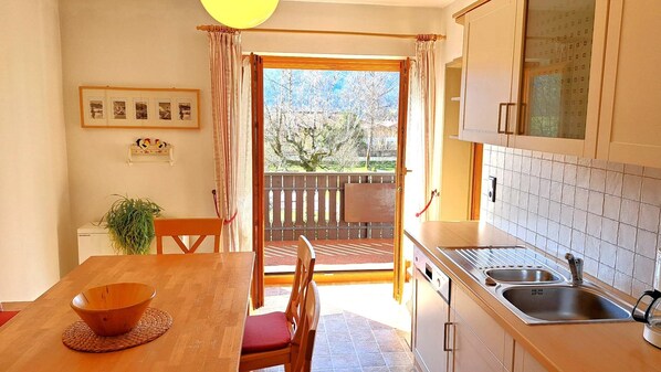A kitchen with a dining area, a view of the outdoors, and a balcony.