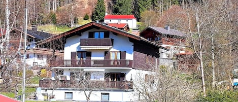 A multi-story building with a balcony, a red roof, and a sign that reads "Gästehaus im Dinkel".