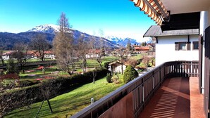 A balcony with a view of a mountainous landscape, a village, and a clear sky.