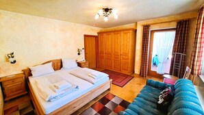 A bedroom with a bed, wooden wardrobe, and a sofa.