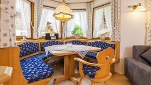 Una habitación acogedora con una mesa de madera, asientos de estampado azul y una lámpara colgante.