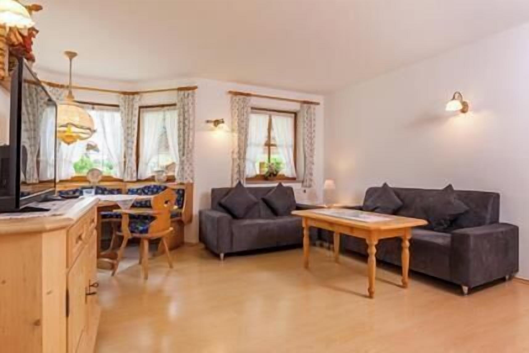 A cozy living room with a sofa, a dining table, and a TV.