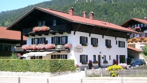 A traditional Alpine-style building with multiple windows and balconies adorned with flowers. - Ferienwohnung (5) (Reit im Winkl)