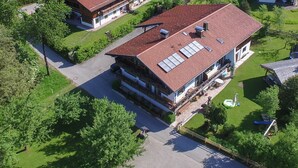 Ein mehrgeschossiges Gebäude mit rotem Ziegeldach, Solaranlage und einer Terrasse mit Sitzgelegenheiten im Freien.