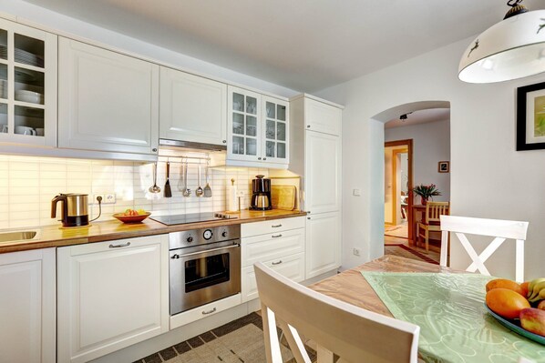 A modern kitchen with white cabinets, stainless steel appliances, and a dining area with a table and chairs.