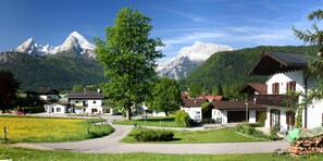 A village with traditional houses, a clear sky, and snow-capped mountains in the background.