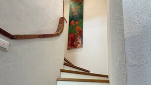 A staircase with wooden steps and white walls, a painting on the wall, and a smoke detector. - Ferienwohnung "Geniessen" für 2-8 Personen, 4 Schlafzimmer, 2 Bäder (Breitbrunn am Chiemsee)
