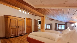 Una camera da letto con soffitto in legno, un letto grande, un armadio e una televisione.
