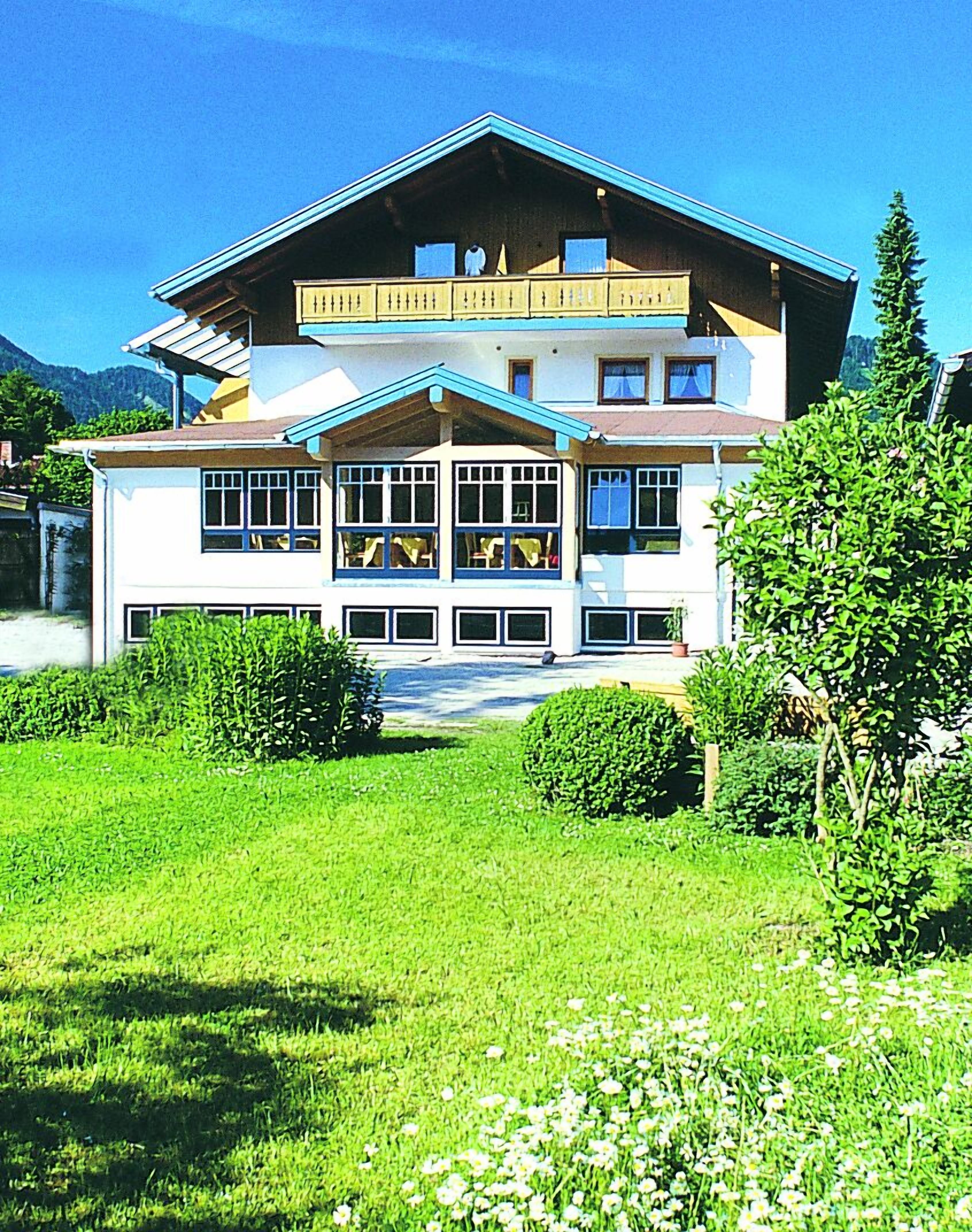 Un immeuble de deux étages doté d’un balcon, de grandes fenêtres et d’une pelouse bien entretenue.