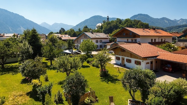 A residential area with houses, a church, and mountains in the background. - 10 Apartment type D 71 sqm, balcony, 2 bedrooms, living room, max 4 p, WLAN (Ruhpolding)