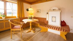 Une pièce chaleureuse avec un plafond en bois, une table ronde entourée de chaises, un banc agrémenté de coussins et une fenêtre avec des rideaux.