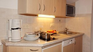 Une cuisine avec des meubles de rangement en bois, un four à micro-ondes, une machine à café et un panier à fruits.