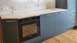A modern kitchen with grey cabinets, a built-in oven, and a marble countertop. - holiday flat (Gstadt am Chiemsee)