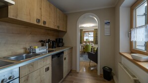 Una cocina compacta con armarios de madera, electrodomésticos de acero inoxidable y vistas a un comedor.