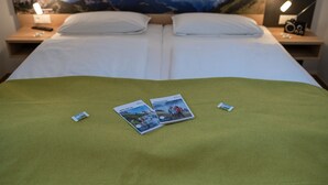 Habitación de hotel con dos camas, un cartel con vista a la montaña y un par de folletos de viaje sobre la cama.