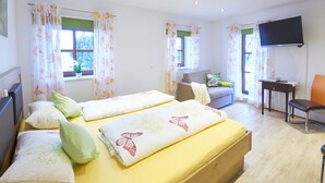 A room with two beds, a sofa, a TV, and a desk.