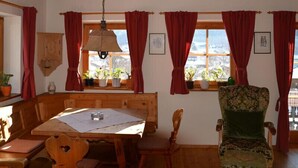 Una habitación acogedora con muebles de madera, una mesa con un papel, una silla y una ventana con cortinas rojas.