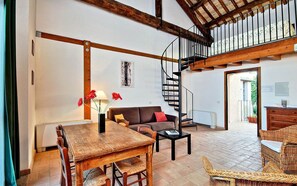 Amplia sala de estar con una mesa de comedor de madera, un sofá y una escalera que conduce a un nivel superior.