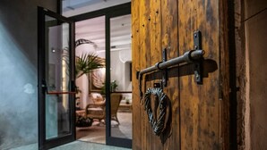 A wooden door with a metal handle and a rope tied to it, leading to an interior space with a visible chair and a plant. - Casale Doria Pamphilj (Fiumicino)