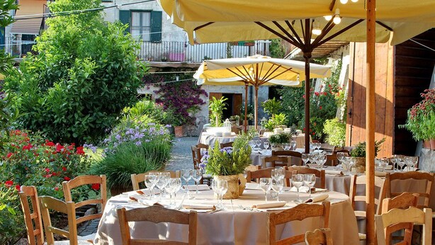 An outdoor dining area with round tables, wooden chairs, and yellow umbrellas. - Casale Doria Pamphilj (Fiumicino)
