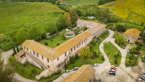 A large, rectangular building with a tiled roof, surrounded by lush greenery and a parking area with several cars. - Casale Doria Pamphilj (Fiumicino)
