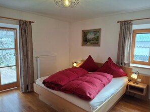 Une chambre à coucher avec un lit, une table de chevet, une lampe, un radiateur et une fenêtre avec des rideaux.