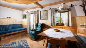 Een gezellige kamer met een houten bank, een tafel met een witte tafelkleed en een stoel met een geruite plaid.