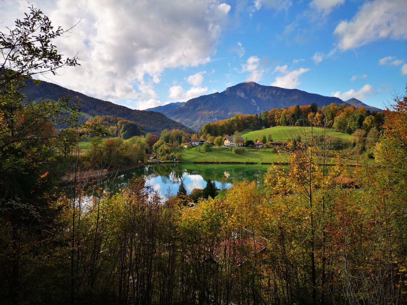 A serene landscape with a lake, houses, and mountains.