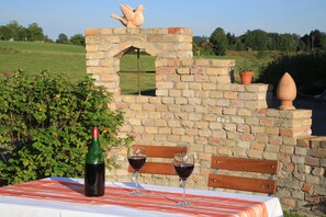 Relax in this charming outdoor seating area with a brick wall, table, and bench.