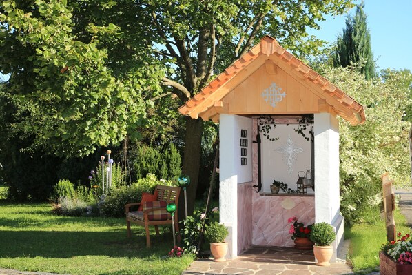 Escape to a serene chapel nestled in a lush garden, offering a peaceful retreat with a simple porch and tranquil surroundings.