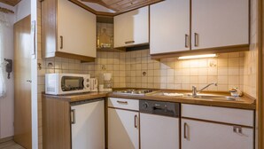 Cuina compacta amb armaris blancs, microones, cafetera i un rentaplat.