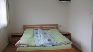 A single bed with a wooden frame and a green mattress, flanked by two bedside tables with lamps. - Ferienwohnung für 1-2 Personen (Marktschellenberg)