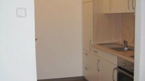 A compact kitchen with light-colored cabinets, a wooden countertop, and a built-in oven. - Ferienwohnung für 1-2 Personen (Marktschellenberg)