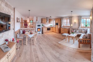 Ferienwohnung Jasmin mit Südterrasse und Bergblick-Wohnraum mit Ecksofa, Essgruppe, Kachelofen und Küche