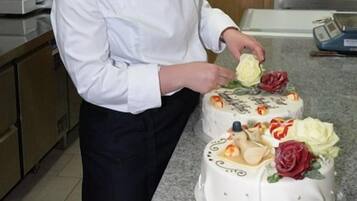 Un chef en una cocina con varios pasteles a la vista.