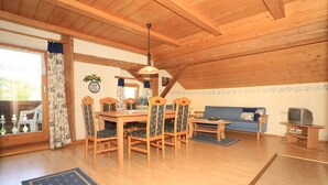 Un comedor con mobiliario de madera, un sofá y una televisión.
