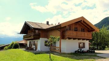 Eine Holzhütte mit Balkon, einem kleinen Garten und Bergblick.