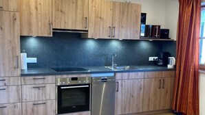 Eine moderne Küche mit Holzausstattung, Edelstahlgeräten und einer schwarzen Arbeitsplatte.
