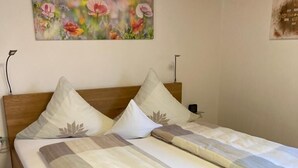 Ein Doppelbett mit Holzrahmen, zwei Kissen und ein Blumenbild an der Wand.