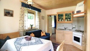 Une pièce chaleureuse comprenant une table à manger, un canapé et un coin cuisine avec des placards et un évier.