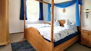 Un lit à baldaquin, une armoire en bois et une table de chevet avec une lampe.