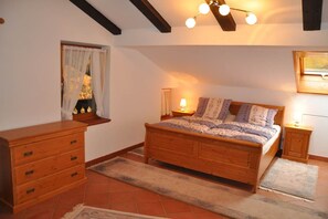A bedroom with a wooden bed, bedside tables, a dresser, and a window with curtains.