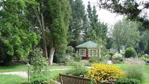 A garden with a gazebo, benches, and various plants.