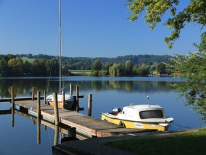 A calm lake with a wooden dock and a small yellow boat docked at the pier.